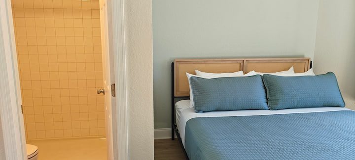 Bedroom with blue bed and adjacent bathroom