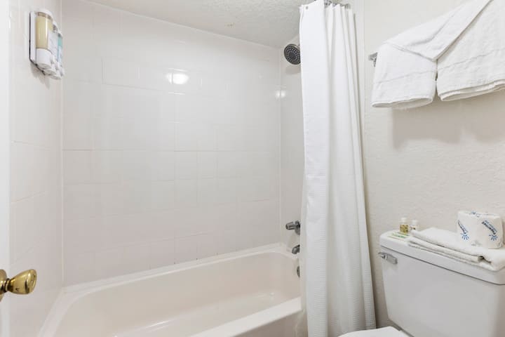 White tiled bathroom with tub and toilet