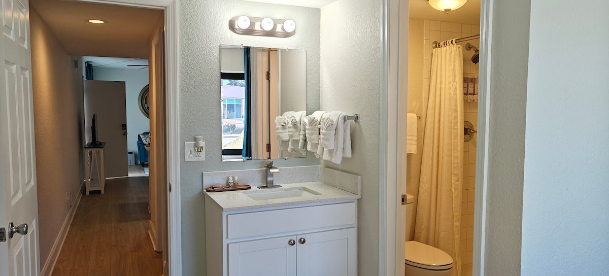 Hallway with white bathroom vanity and shower