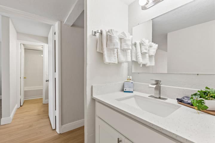 Modern white bathroom vanity with towels, mirror
