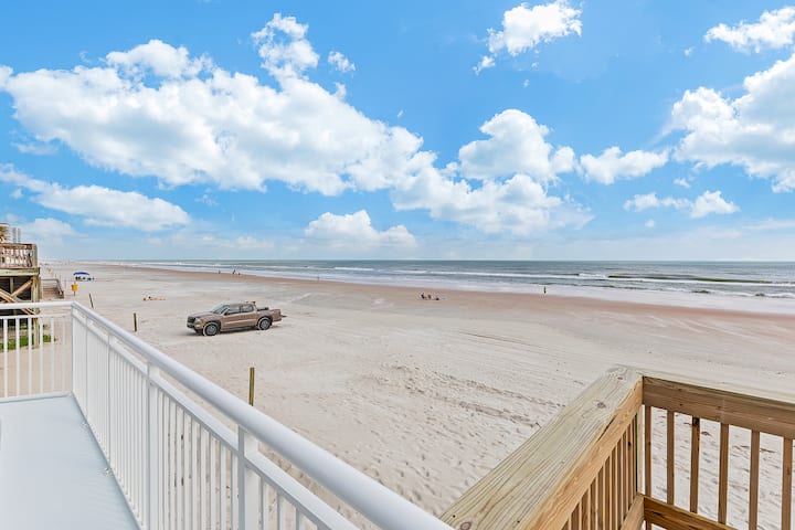 Balcony overlooking sandy ocean beach under cloudy sky