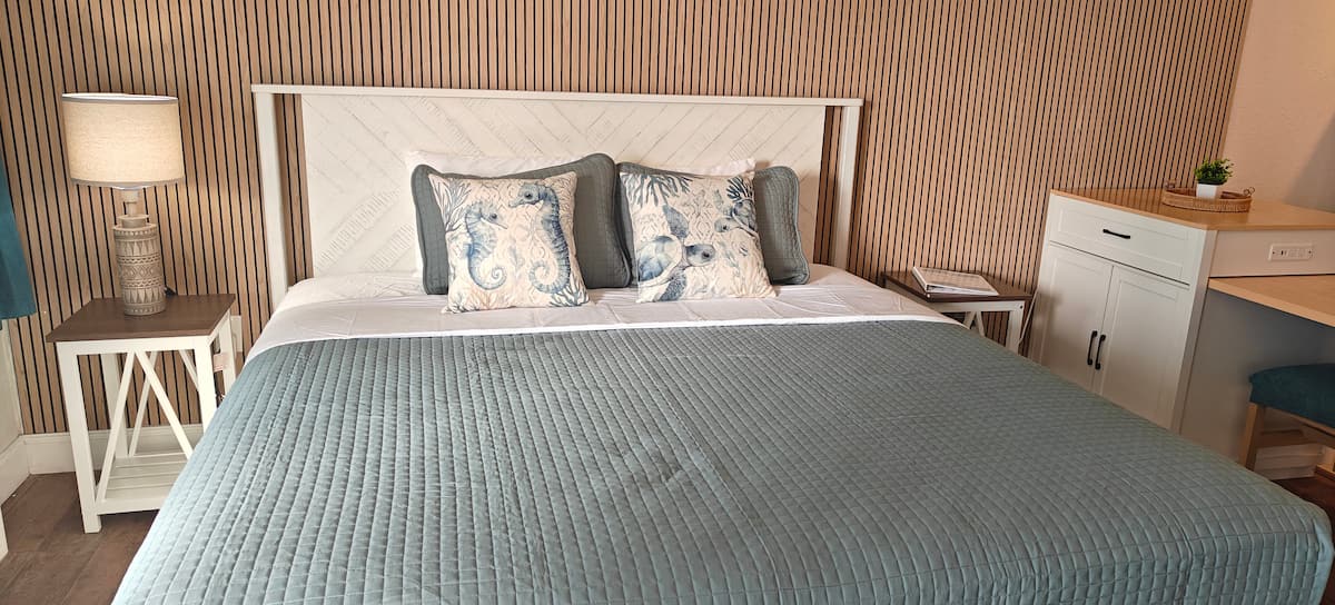 Cozy bed with teal quilt and decorative pillows
