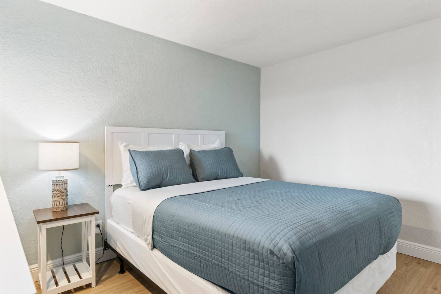 Small bedroom with blue bedding and lamp