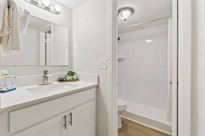 Compact all-white bath with tub and mirror