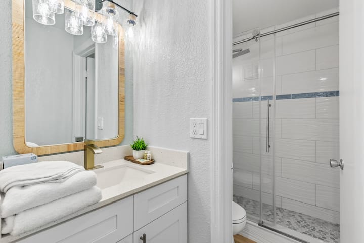 Vanity with wood mirror, white towels, brass faucet
