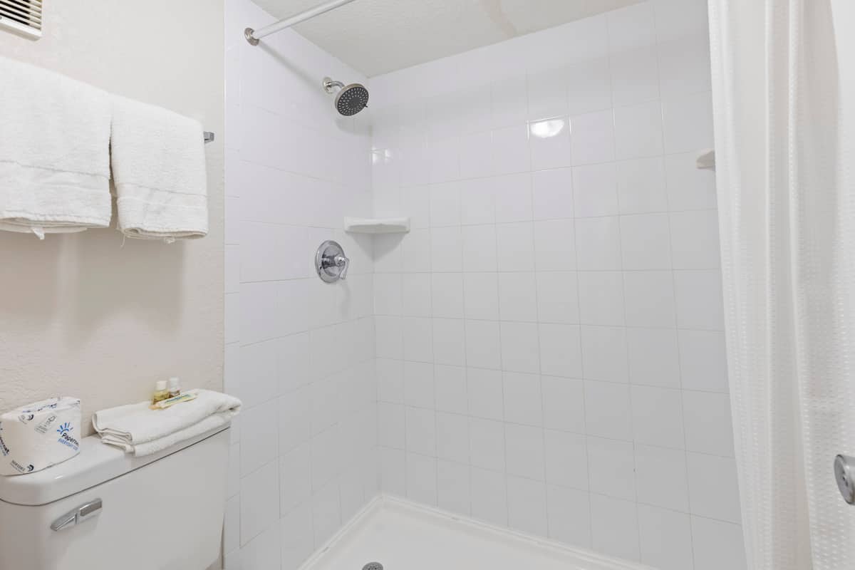 White tiled shower with towels and toiletries