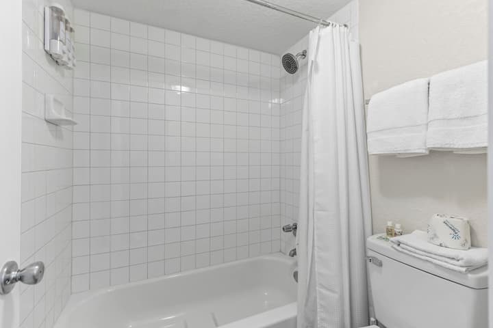 Clean white tiled bathtub with shower curtain