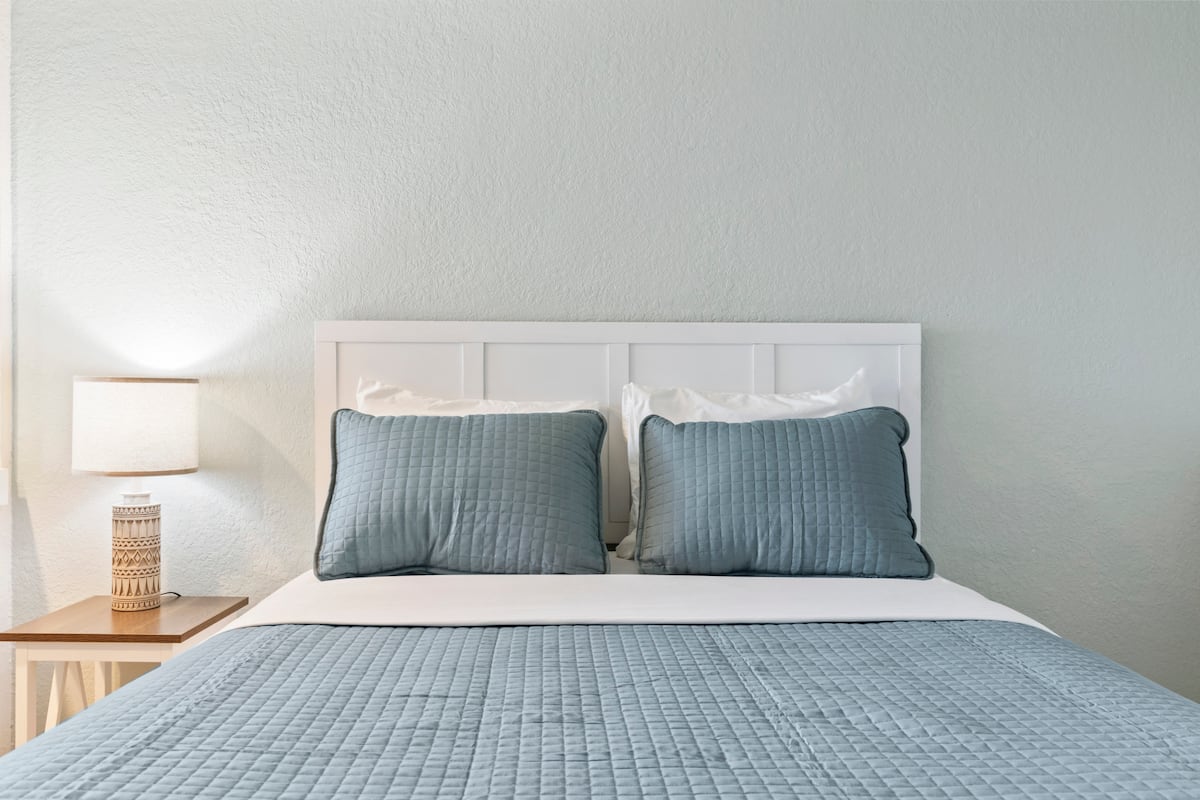 Neatly made bed with blue quilt and pillows