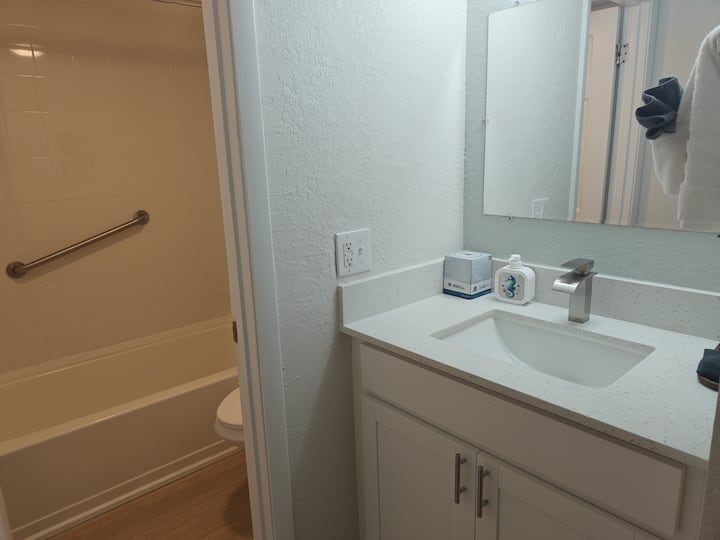 White bathroom vanity with sink and bathtub