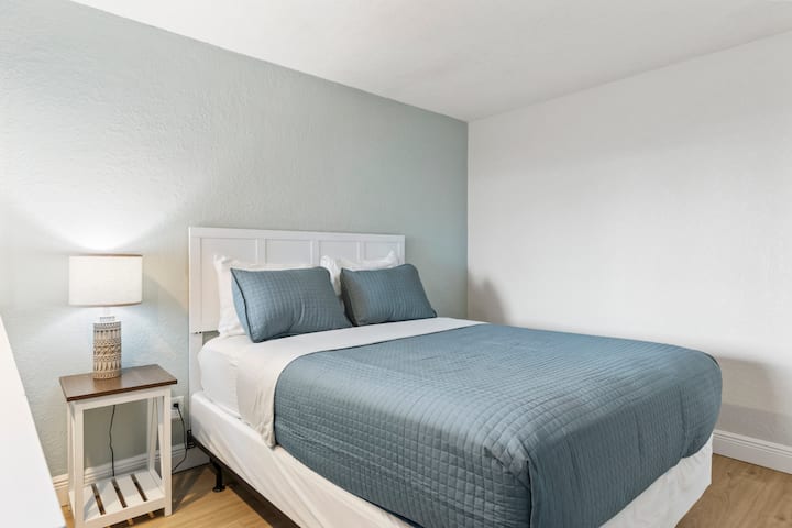 Small bedroom with teal quilt and nightstand lamp