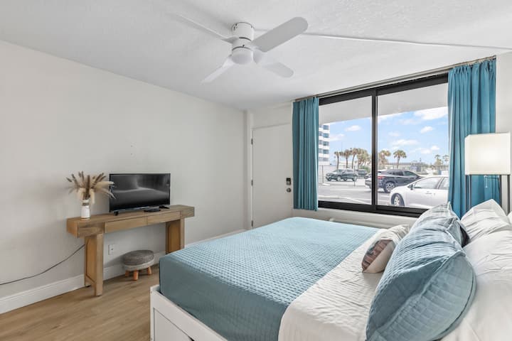 Modern coastal bedroom with teal bedding, palm view