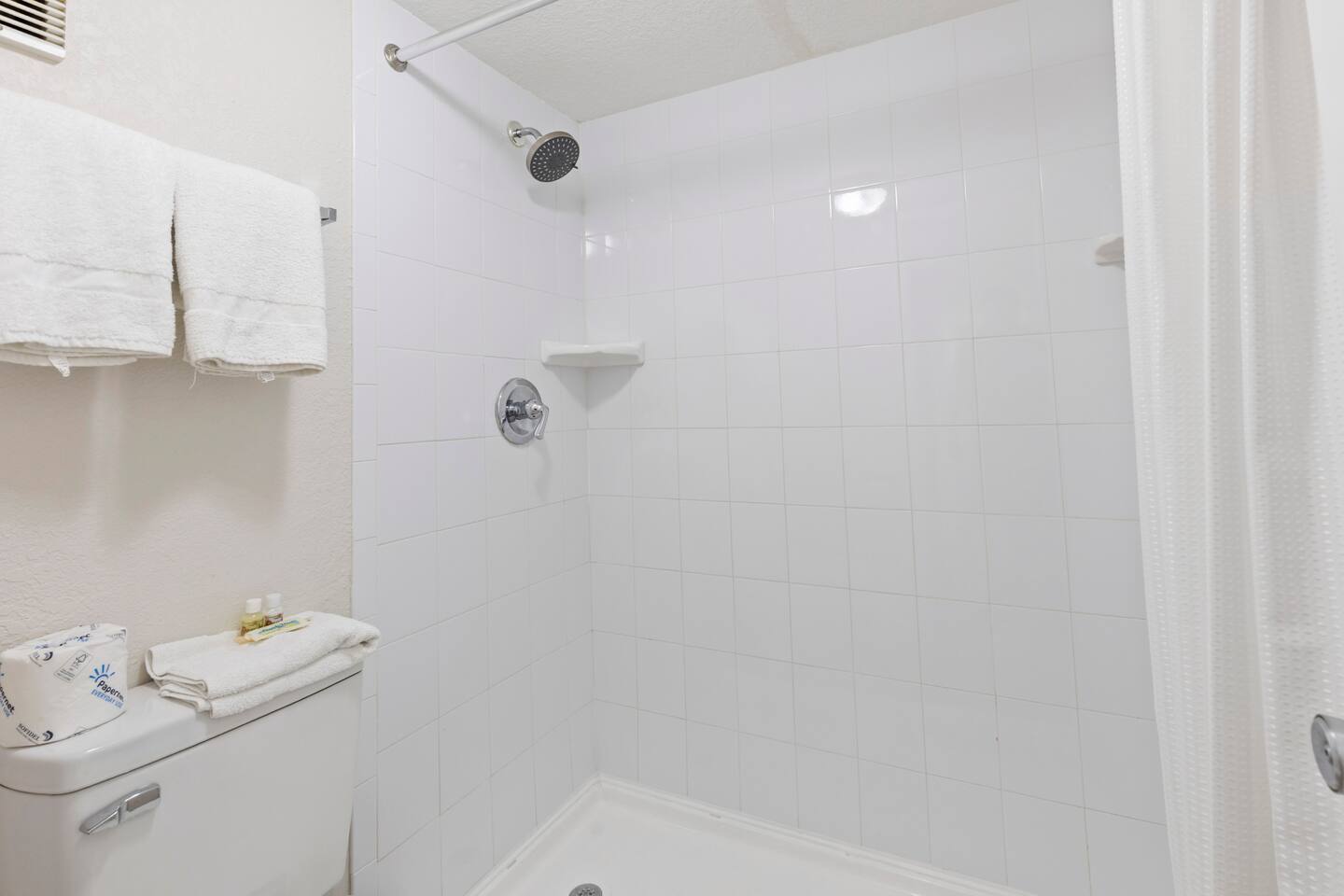 White tiled bathroom shower with towels