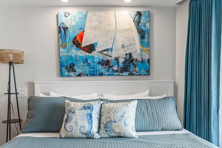 Coastal bedroom with sailboat painting above bed