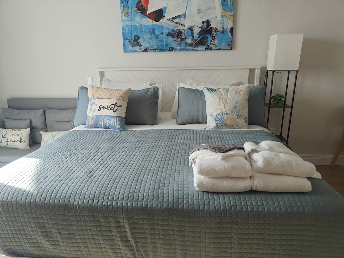 Bed with blue quilt and folded towels