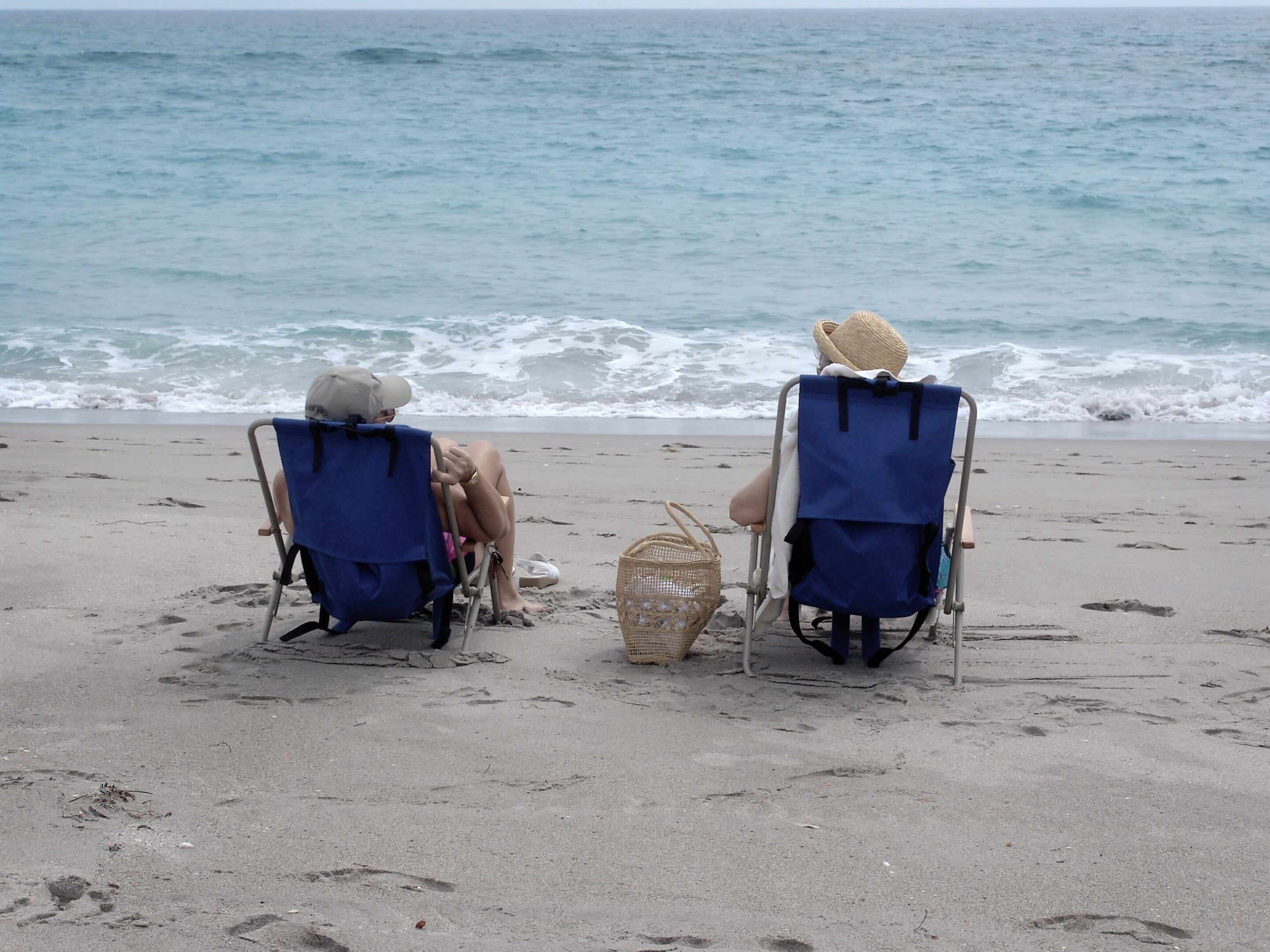 Two people relaxing in beach chairs by ocean