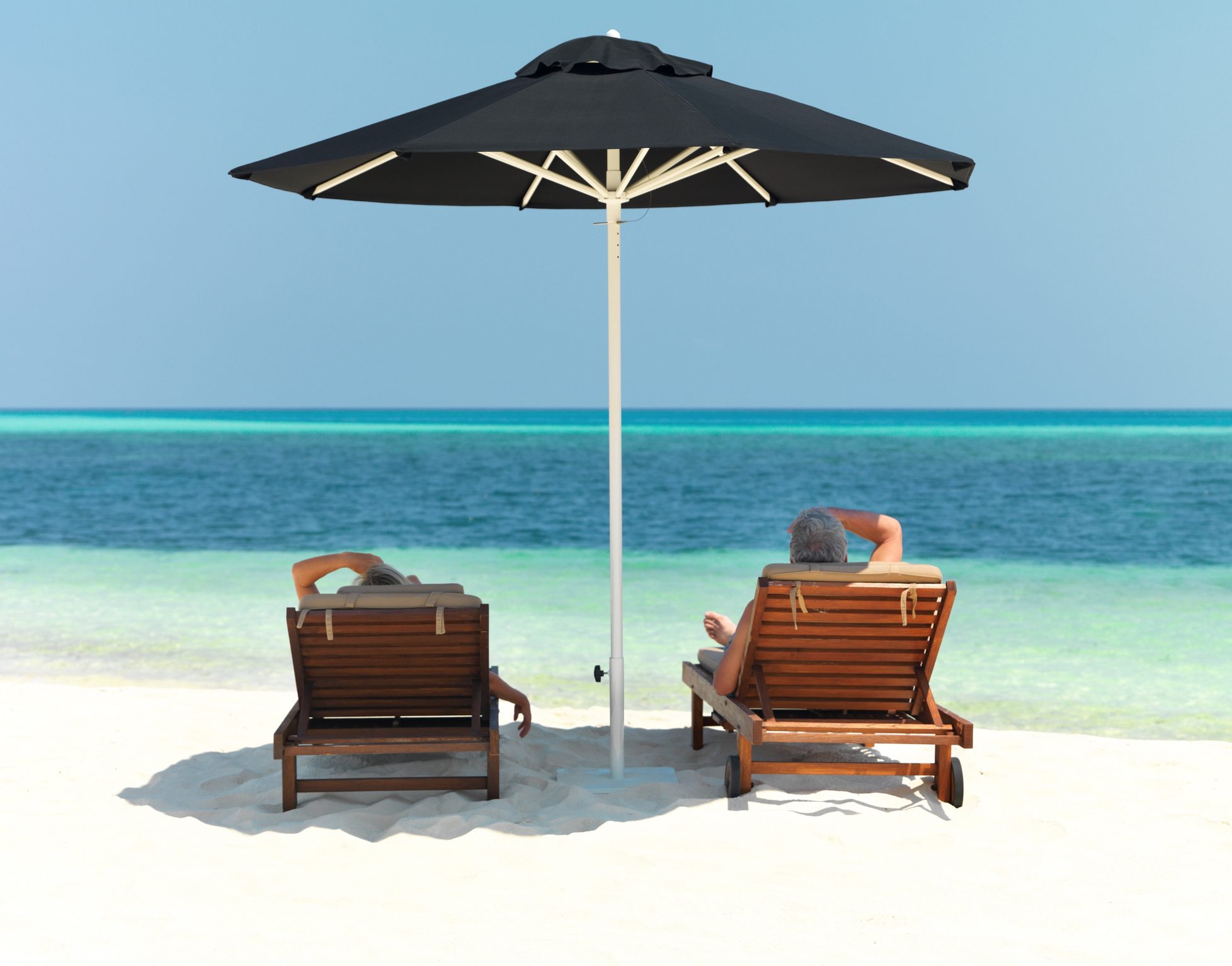 Two lounge chairs under umbrella on beach